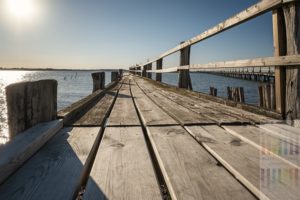 Morscher Holzsteg in Wackerballig an der Ostseeküste im Kreis Schleswig Flensburg im sonnigen Gegenlicht